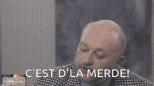 a bald man in a plaid suit and tie is making a funny face .11353329234047127204